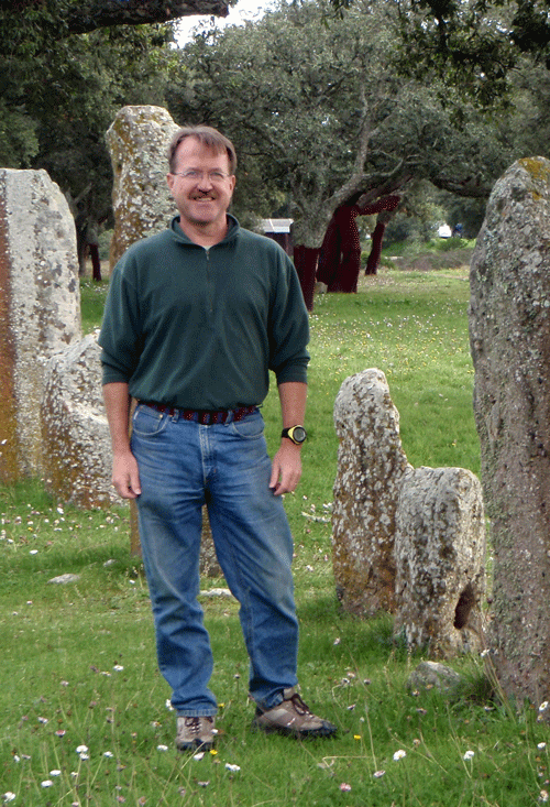 Rich Wanty standing at an archeological site with vertical stones